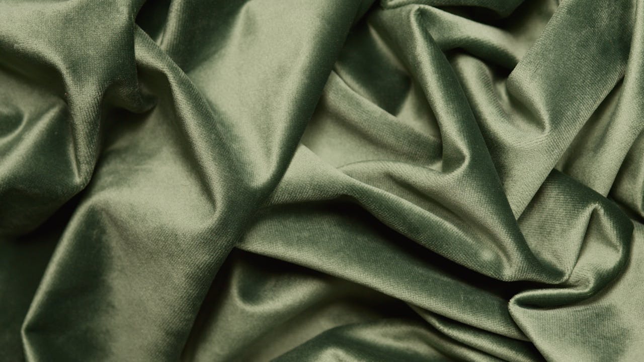 Close-up of luxurious green velvet fabric with elegant folds and smooth texture.